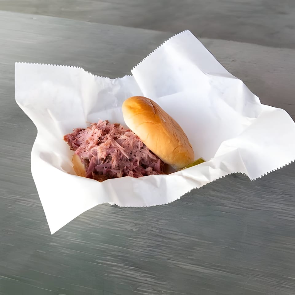 Mosito's BBQ pulled pork sandwich with a bun, served in a white paper tray.